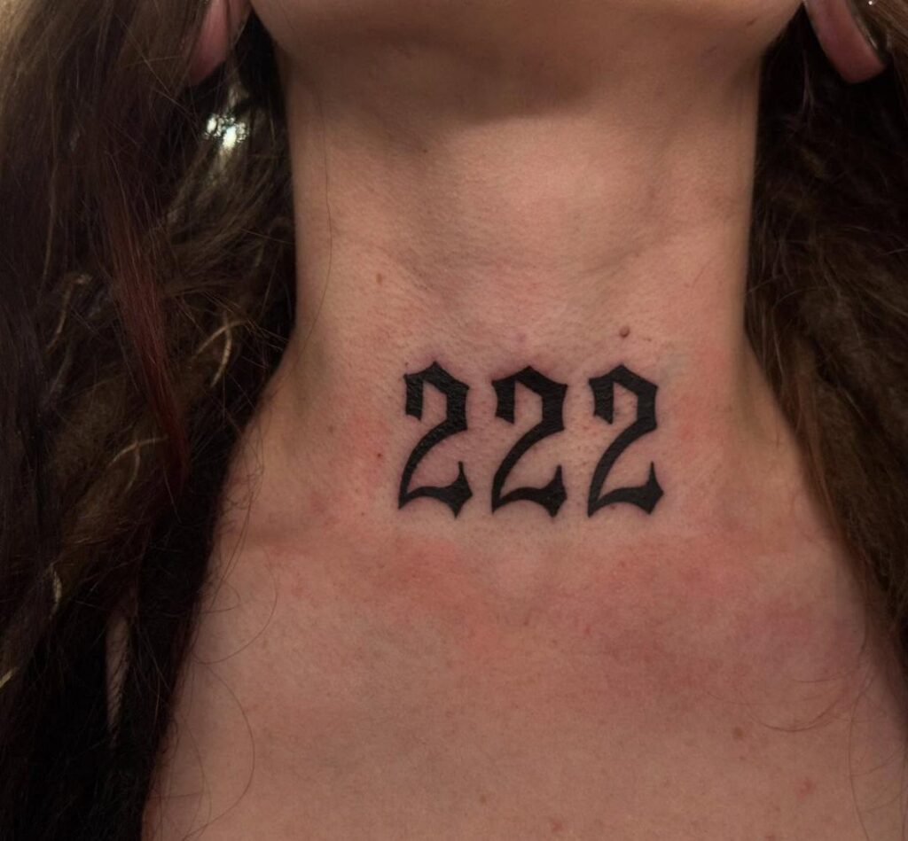 Gothic style 222 angel number tattoo on the front of a person's neck.