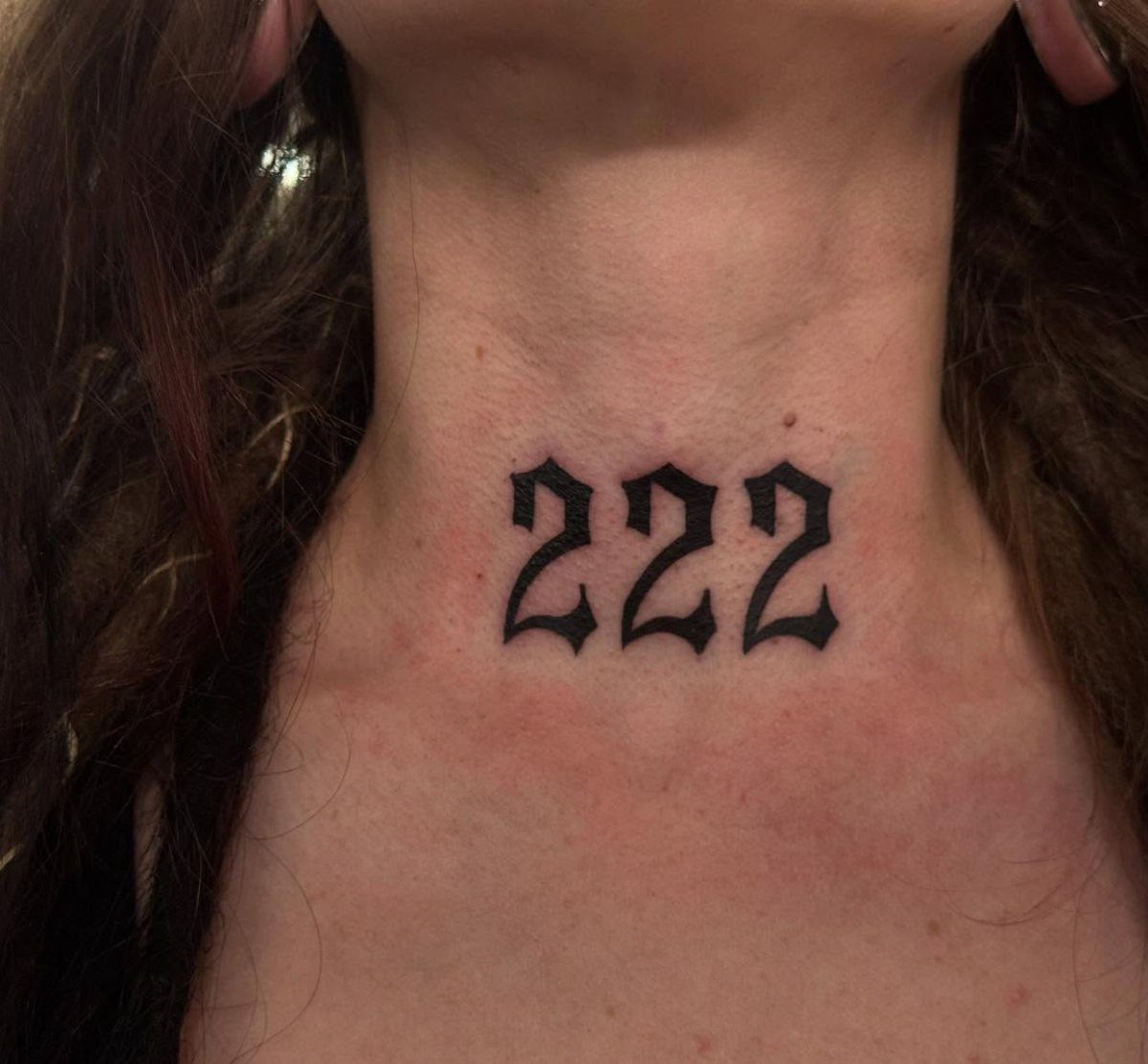 Gothic style 222 angel number tattoo on the front of a person's neck.