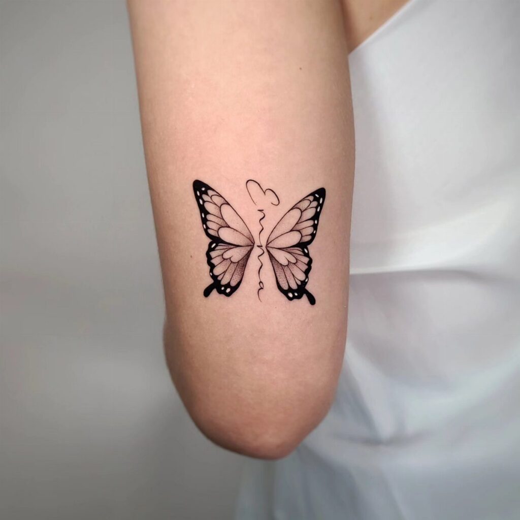 Butterfly tattoo on an arm with a name forming the butterfly's body.