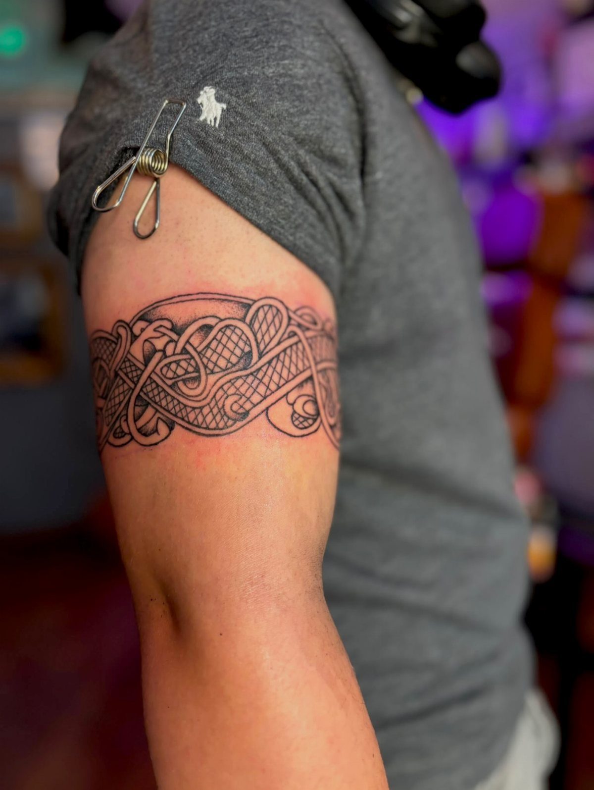 Celtic knot tattoo band wrapped around a person's upper arm in black ink.