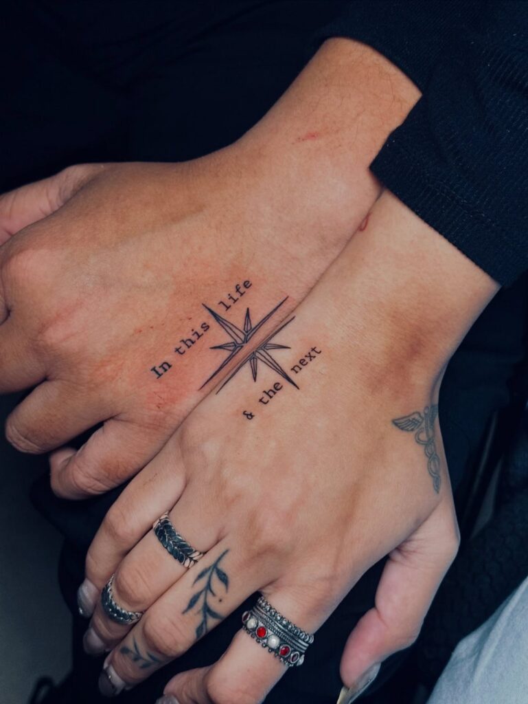 Matching wrist tattoos of a split star and text on two people's arms.