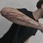 Cursive lettering tattoo of the word Resilience on a person's forearm