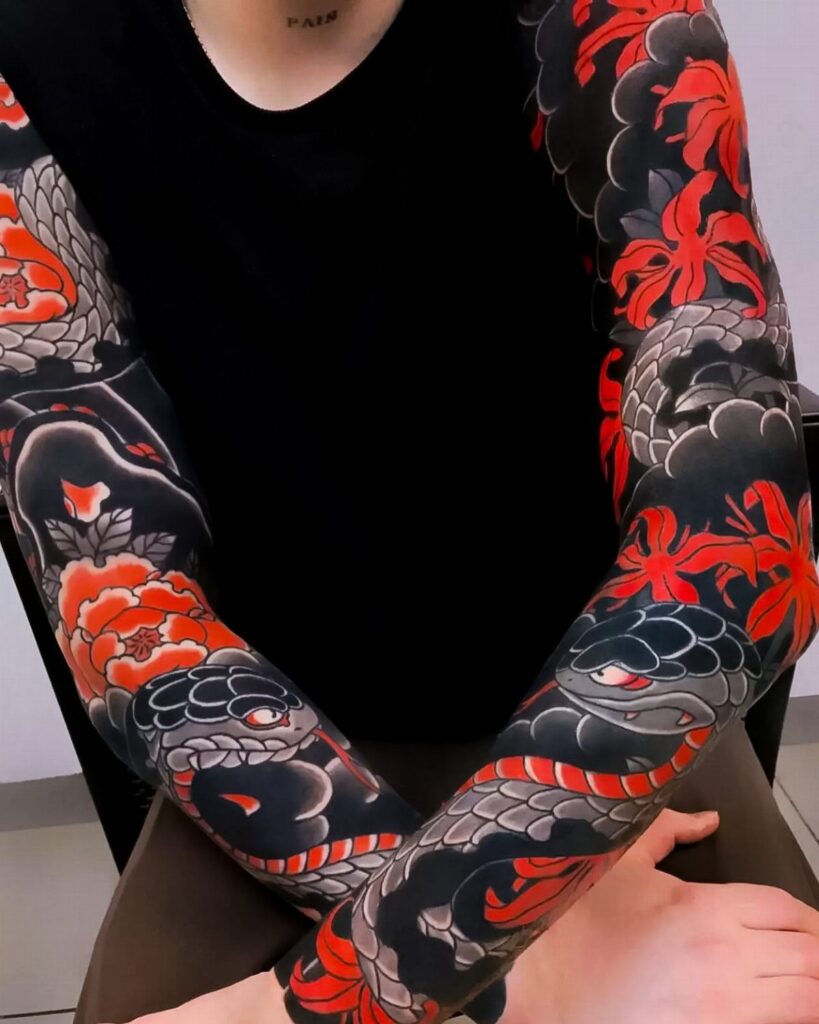 Full sleeve Japanese tattoos with red flowers and snakes on a person's arms