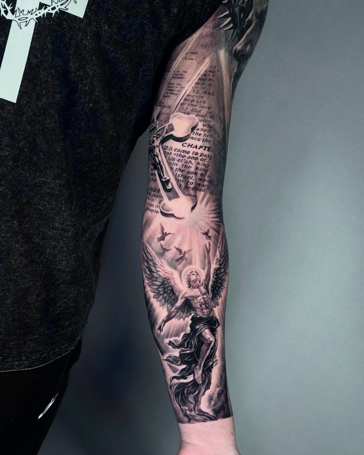 Jesus tattoo with large angel wings and a halo on a forearm