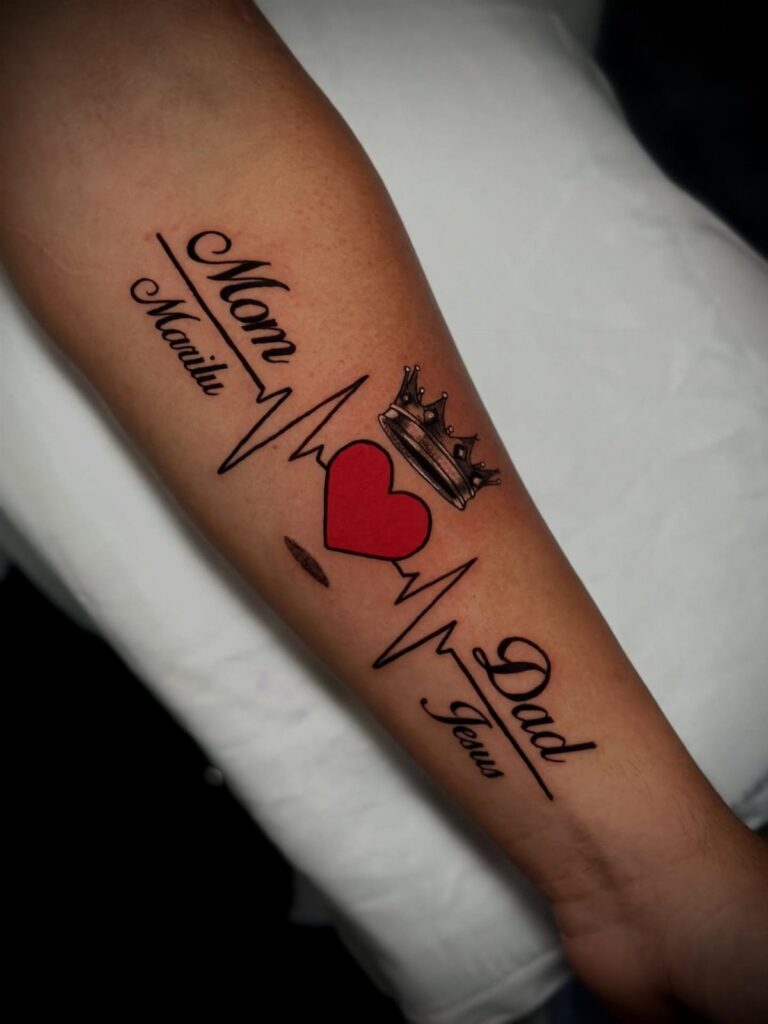 Forearm tattoo with a red heart, crown, and text reading Mom and Dad.