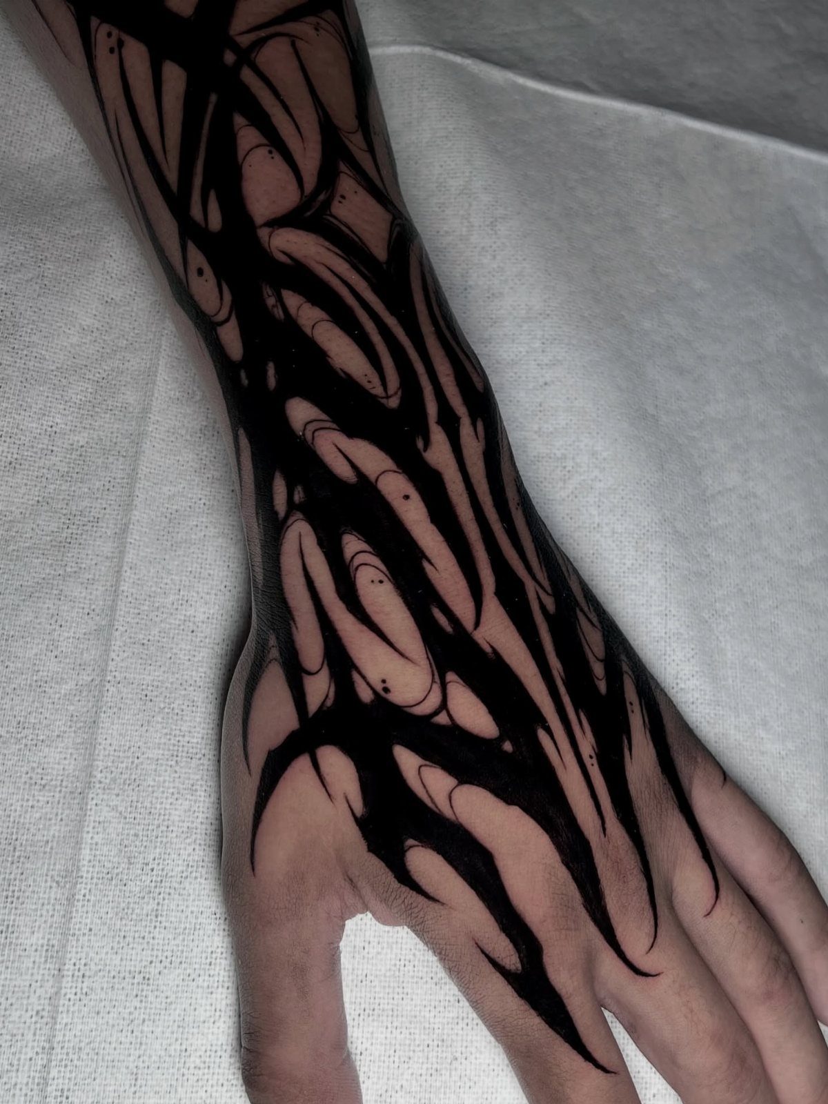 Neo tribalism tattoo with bold black abstract lines on a hand and forearm.