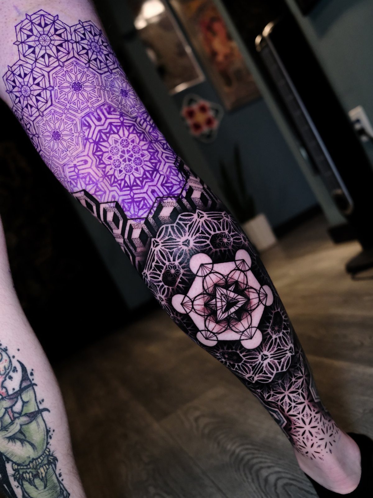 Intricate sacred geometry tattoos with purple and black mandalas on a person's arm.