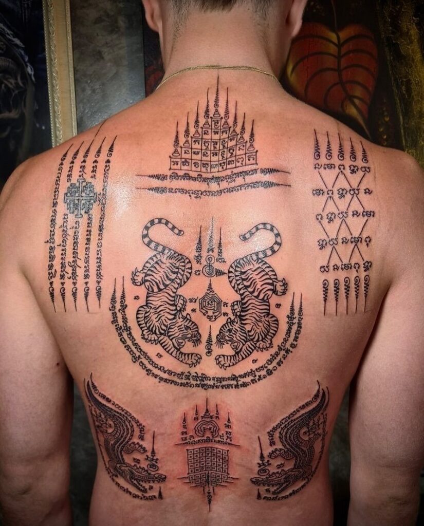 Back of a man with traditional black ink sak yant tattoos including tigers.