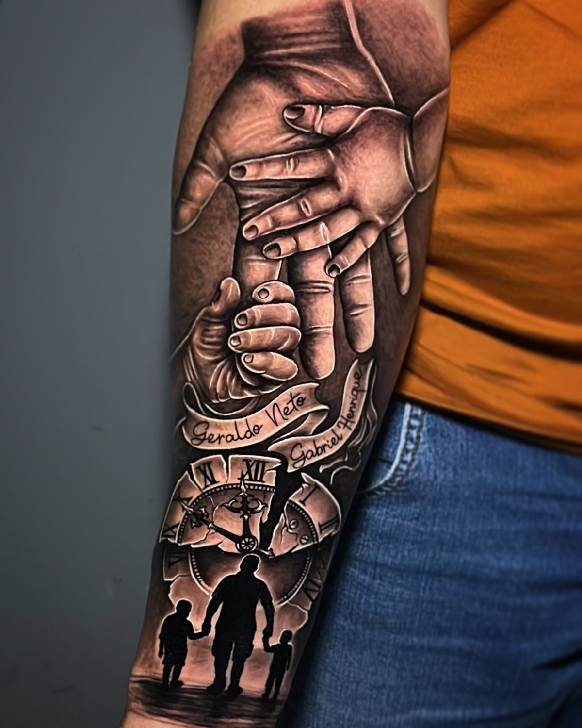 Black and grey forearm tattoo showing a father's hand holding a child's hand.