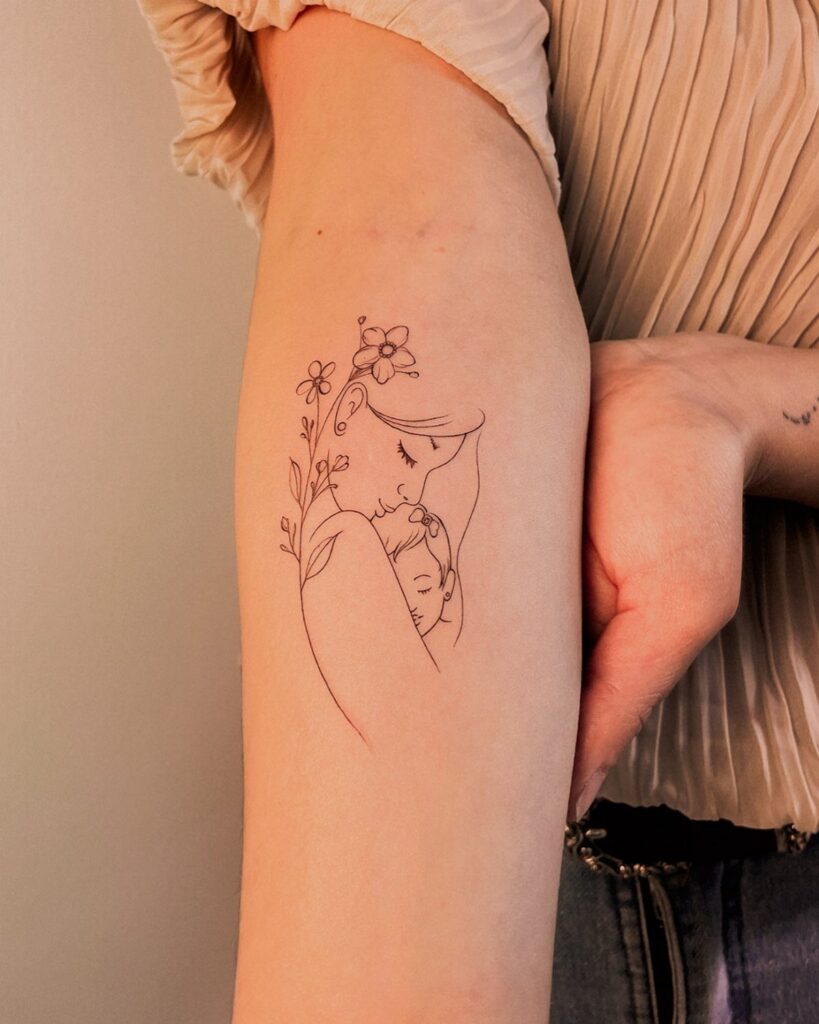 Fine-line tattoo of a mother and child embracing with flowers on an arm