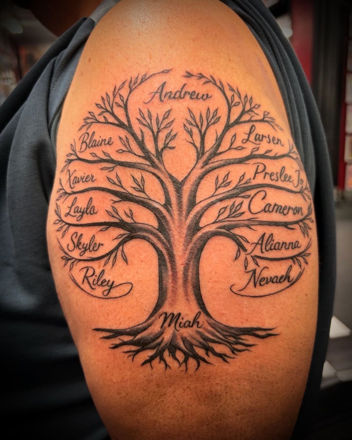 Family tree tattoo on an arm featuring names integrated into the branches