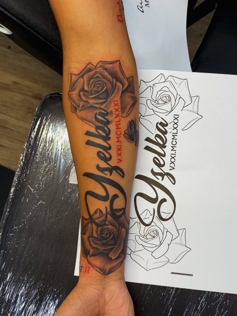 Forearm tattoo of the name Yzelka surrounded by two detailed black and grey roses.