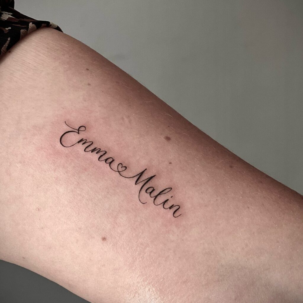 Cursive tattoo of the names Emma and Malin connected by a heart