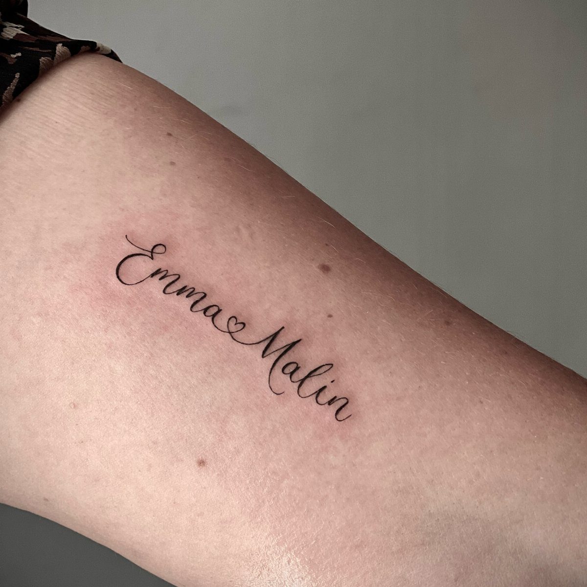 Cursive tattoo of the names Emma and Malin connected by a heart