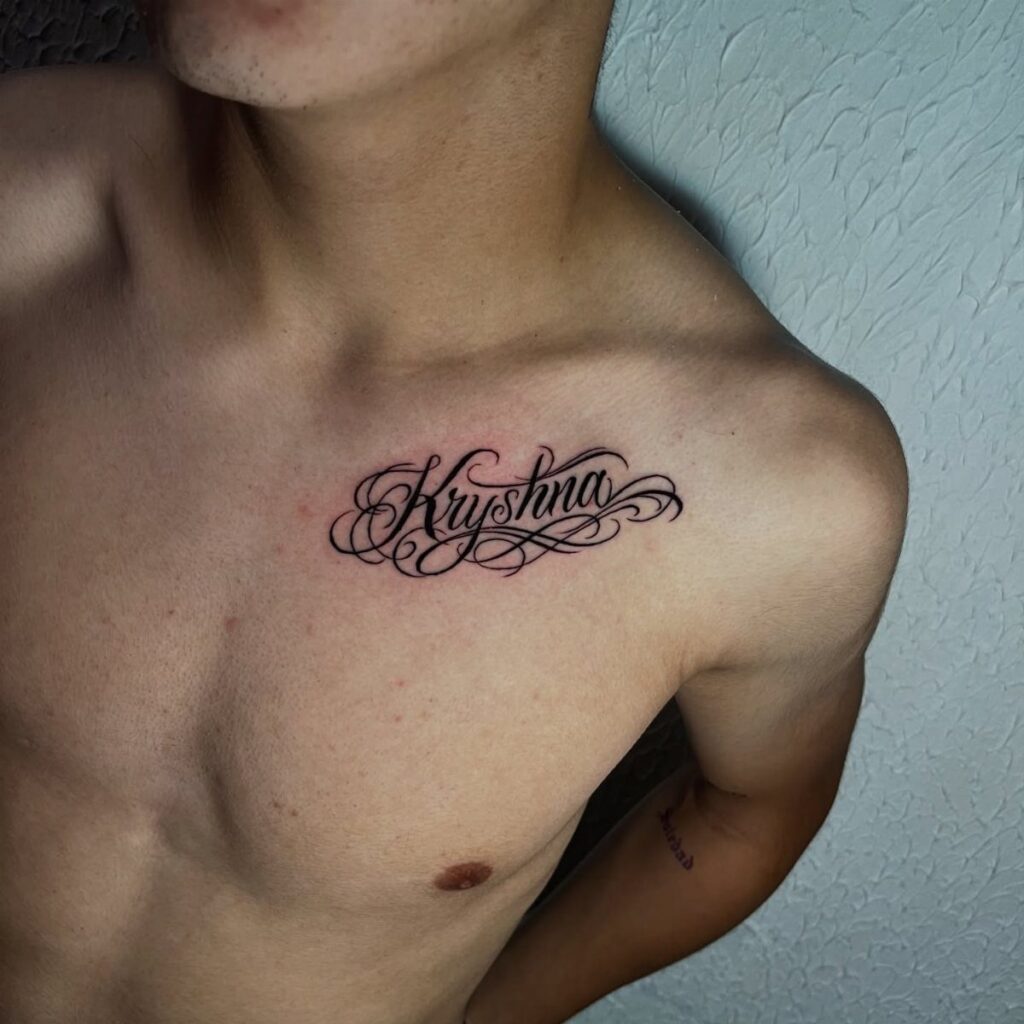 Black script name tattoo on a person's upper chest near the collarbone.