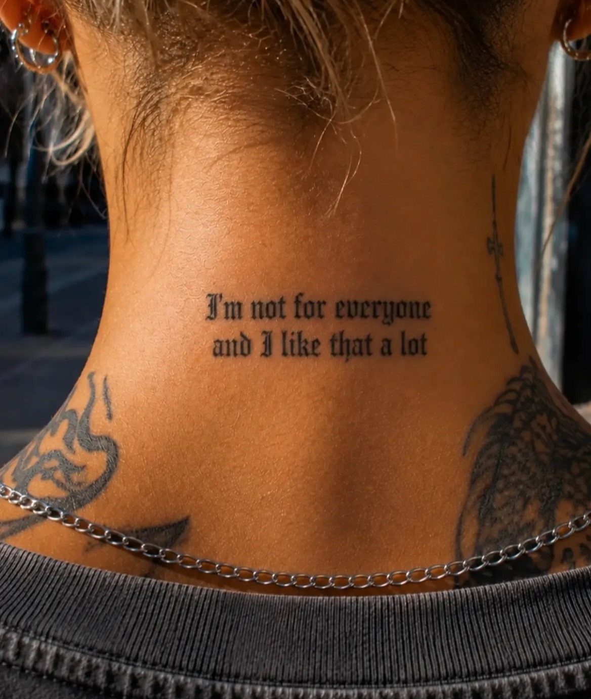 Gothic word tattoo on the back of a woman's neck reading I'm not for everyone