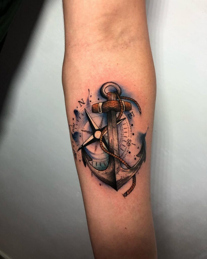 Anchor tattoo with rope and compass rose on a person's forearm.