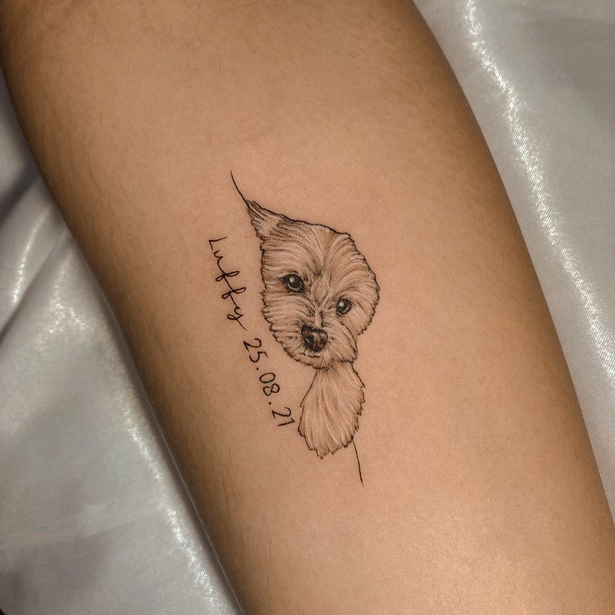 Realistic dog portrait tattoo with name and date on a person's forearm