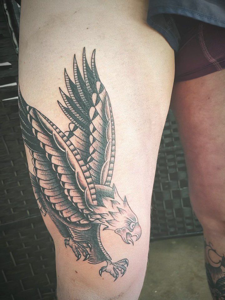 Eagle tattoo in traditional American style on a person's thigh with bold shading.