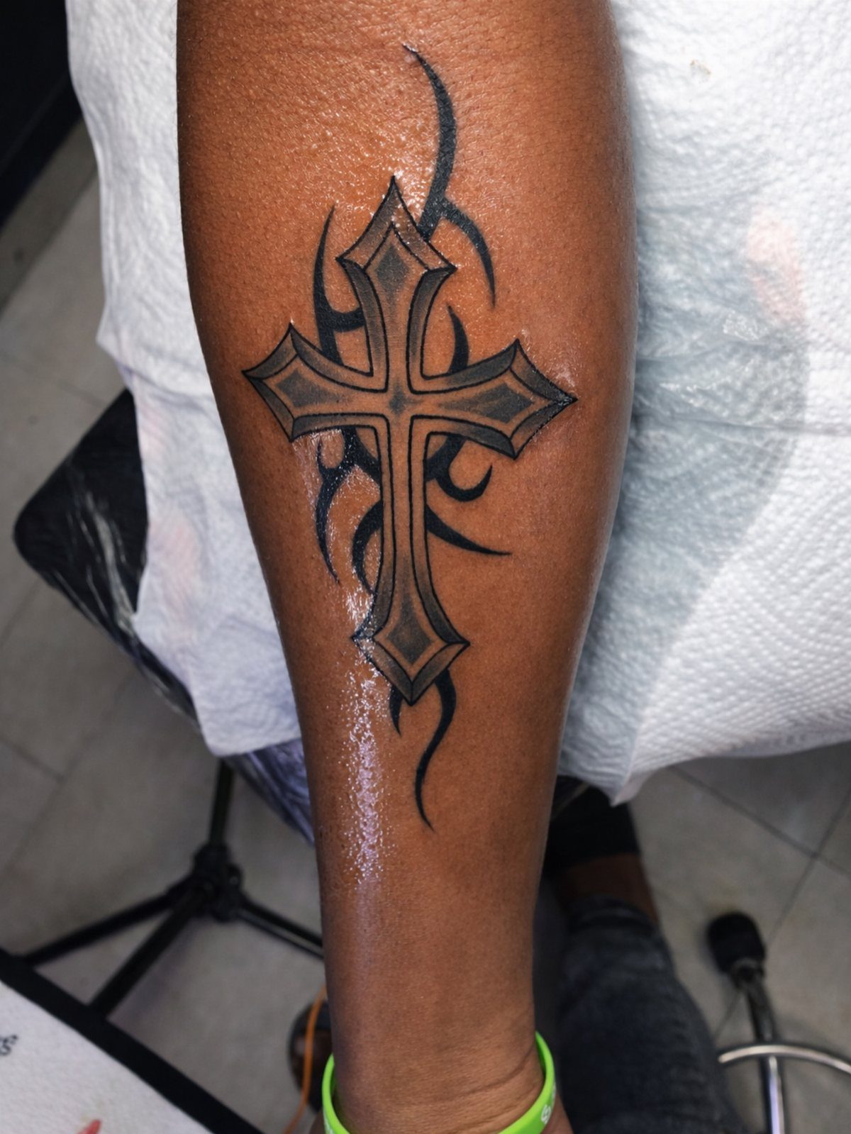 Tribal cross tattoo with sharp edges and curved black lines on a forearm